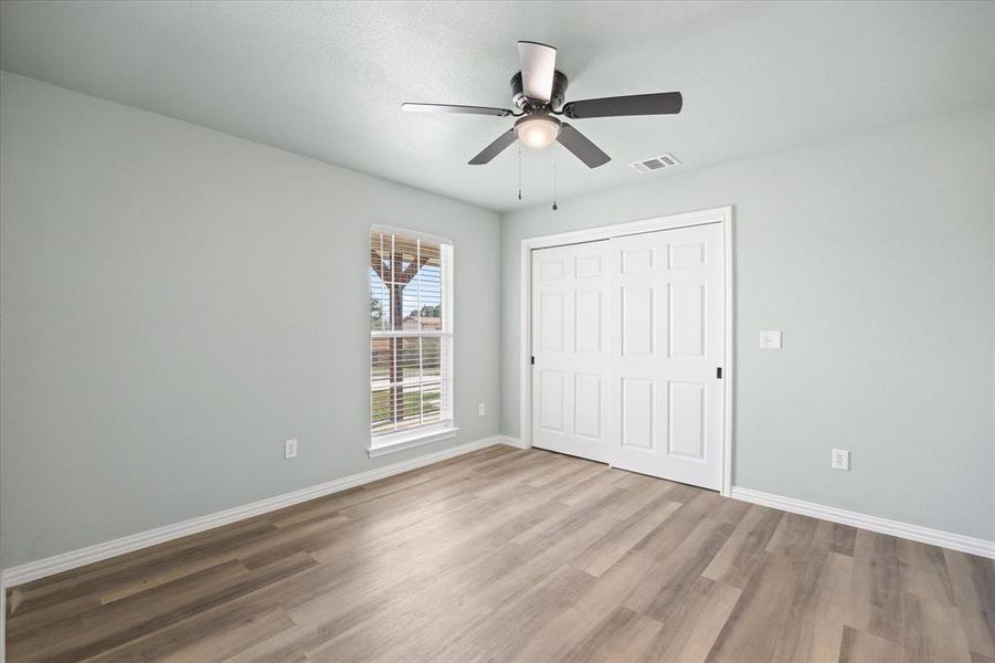 Unfurnished bedroom with ceiling fan, a closet, and hardwood / wood-style flooring