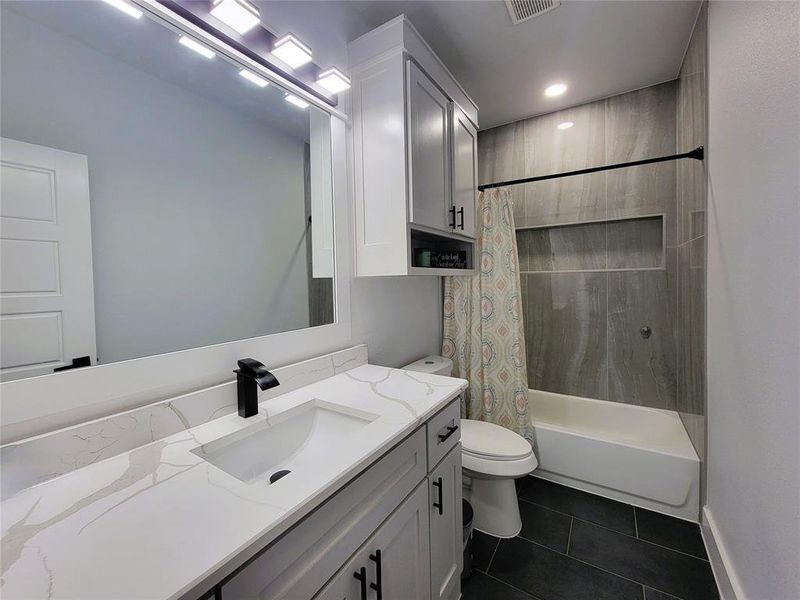 Hall Full bath featuring vanity, shower / tub combo, and dark tile patterned floors