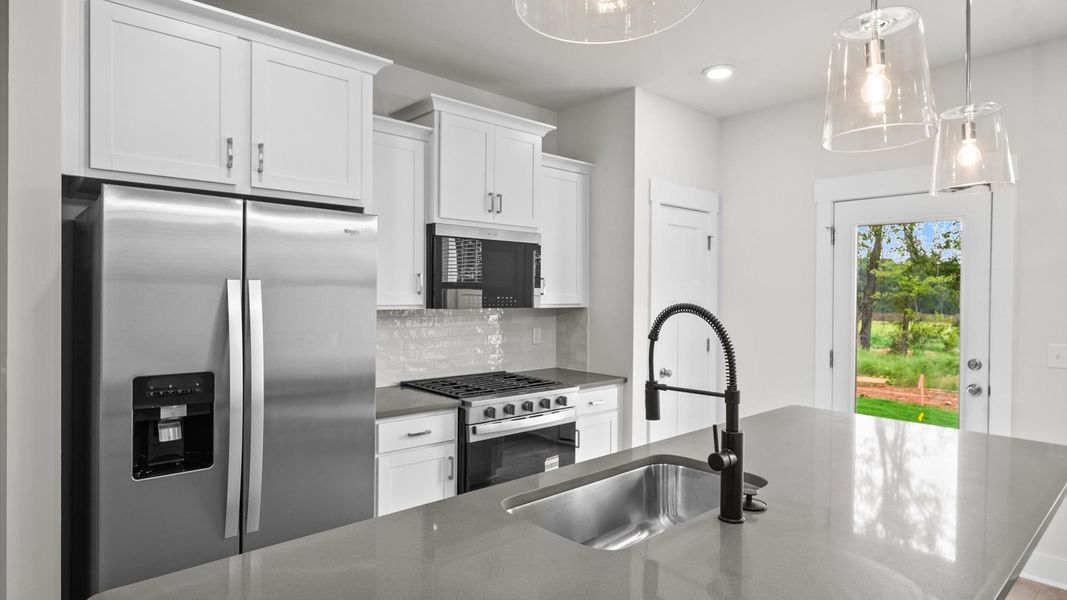 Exclusive DRB Homes kitchen with a 9-foot island, elevated finishes, and pendant lighting in a prime location Exclusive DRB Homes kitchen with a 9-foot island, elevated finishes, and pendant lighting in a prime location