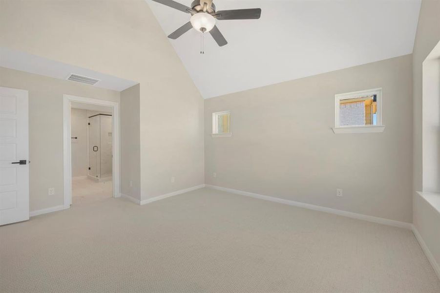 Empty room featuring a ceiling fan, lofted ceiling, and carpet flooring
