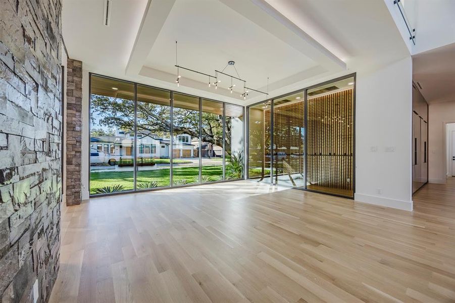 Spare room featuring light wood-style floors, expansive windows, a tray ceiling, a residential view, and rail lighting Spare room featuring light wood-style floors, expansive windows, a tray ceiling, a residential view, and rail lighting