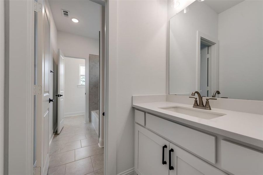 Bathroom with tiled shower / bath, tile flooring, and vanity