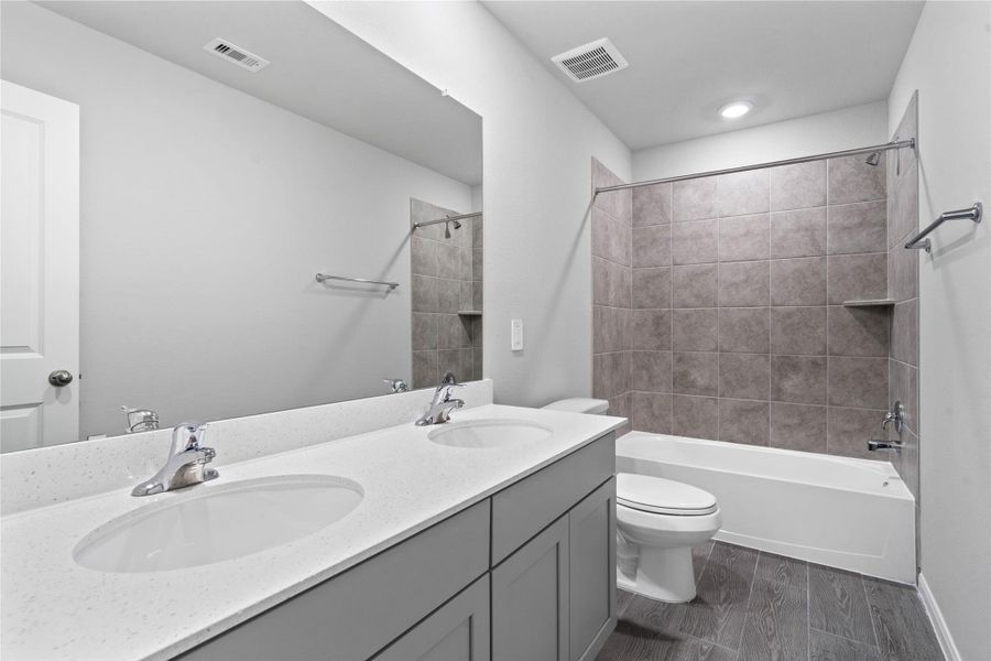 A streamlined secondary bathroom providing a functional tub/shower combination, dual sink vanity with modern fixtures seamlessly blending practicality and style.