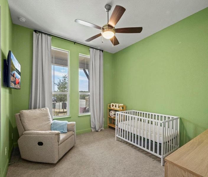 Carpeted bedroom with baseboards, a crib, and ceiling fan