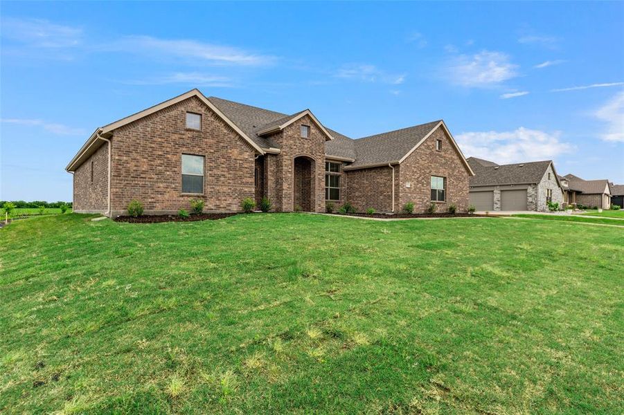 View of front of house featuring brick siding, an attached garage, and a front yard