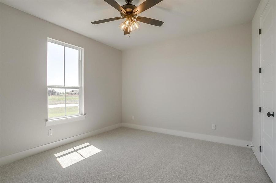 Carpeted spare room featuring baseboards and a ceiling fan Carpeted spare room featuring baseboards and a ceiling fan