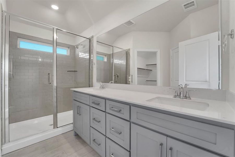 Bathroom featuring double vanity, a sink, visible vents, and a shower stall