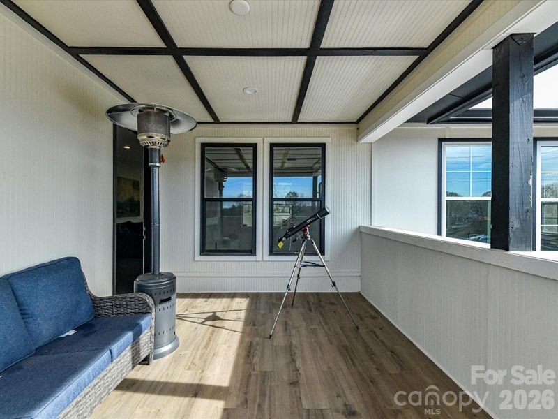 Covered patio with stylish wood flooring, a cozy seating area & amazing water views!