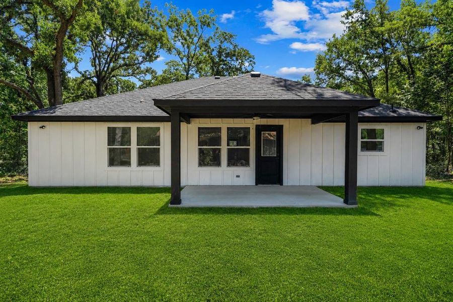Rear exterior with a covered concrete patio and a black shingle roof Rear exterior with a covered concrete patio and a black shingle roof
