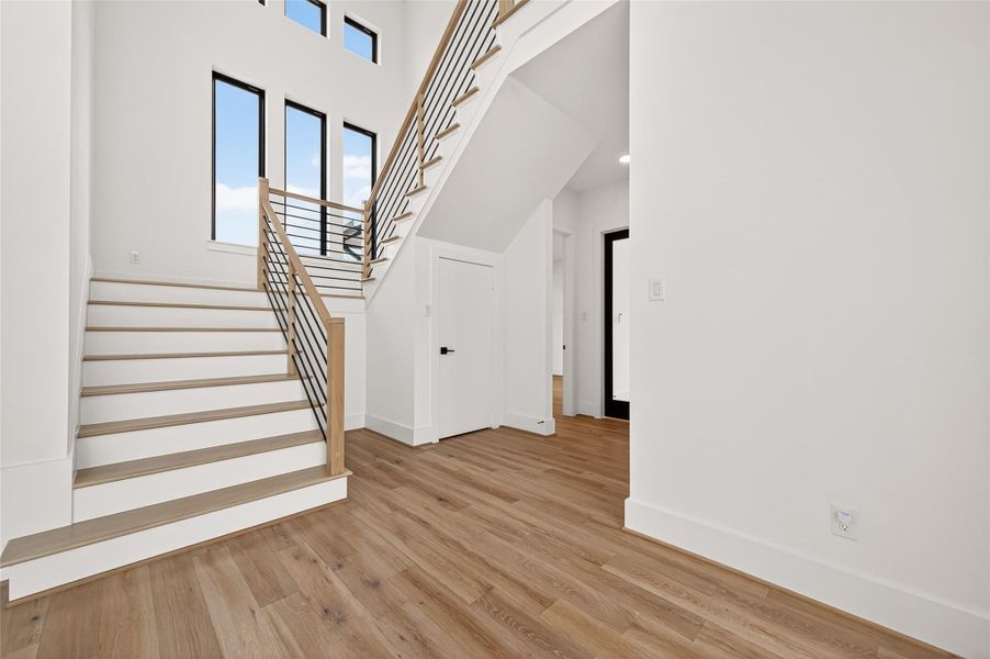 A stunning modern staircase featuring wood treads with iron and wood accents leads to the second floor, adding architectural beauty to the heart of the home.