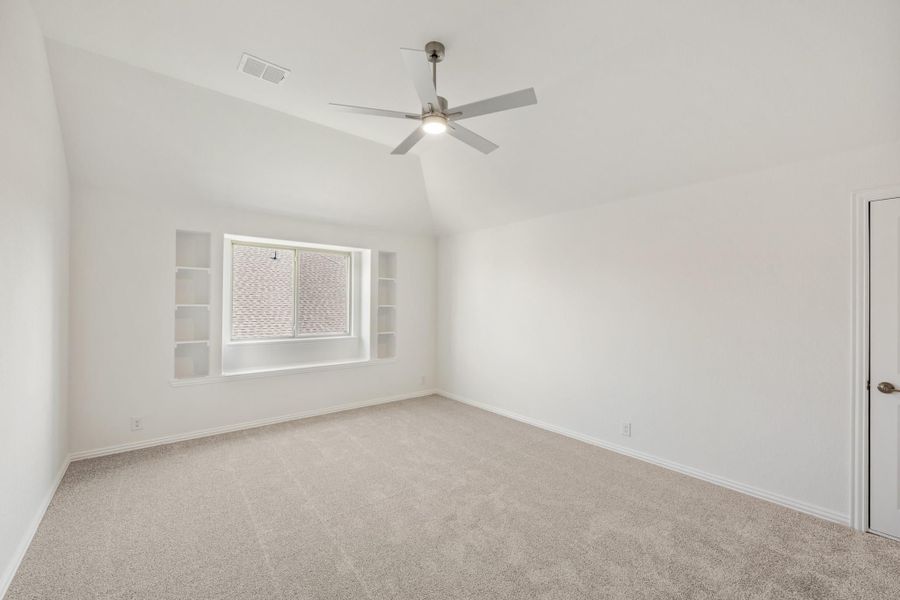 Empty bedroom with vaulted ceiling, ceiling fan, built-in shelves, and carpet flooring Empty bedroom with vaulted ceiling, ceiling fan, built-in shelves, and carpet flooring