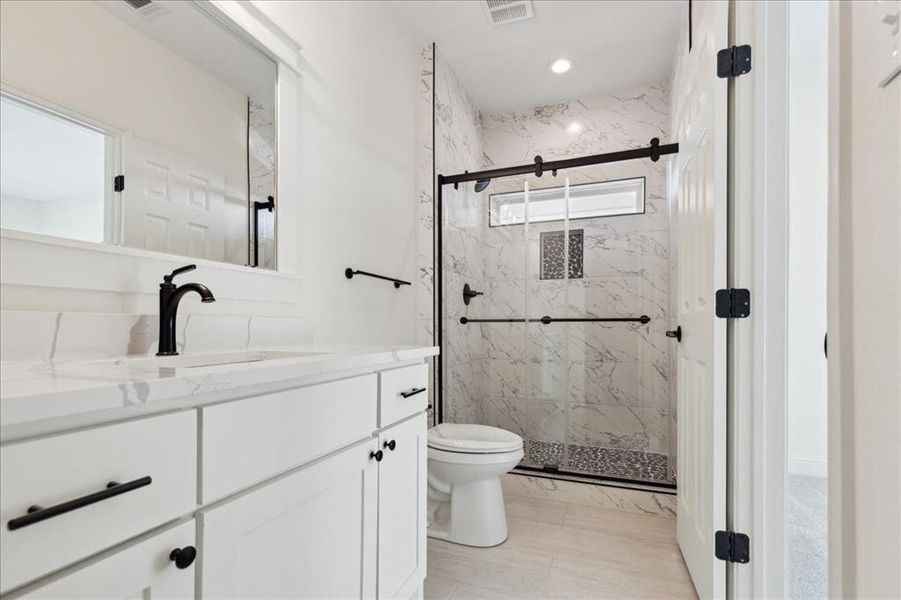 Bathroom featuring toilet, a shower with door, and vanity