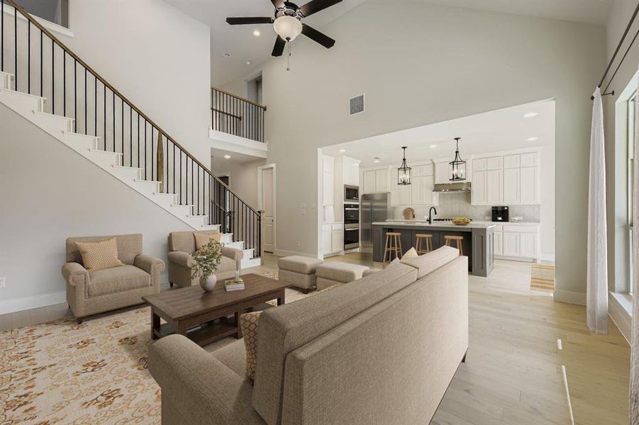 Virtually staged photo - Living area with light wood-style floors, ceiling fan, a high ceiling, and recessed lighting