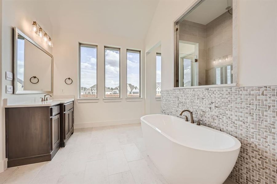 Bathroom featuring tile walls, vaulted ceiling, vanity, plus walk in shower, and tile patterned floors