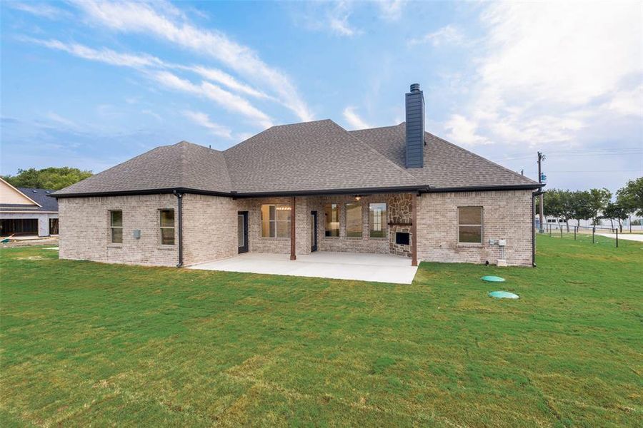 Back of property with a lawn, a patio, brick siding, and a shingled roof Back of property with a lawn, a patio, brick siding, and a shingled roof