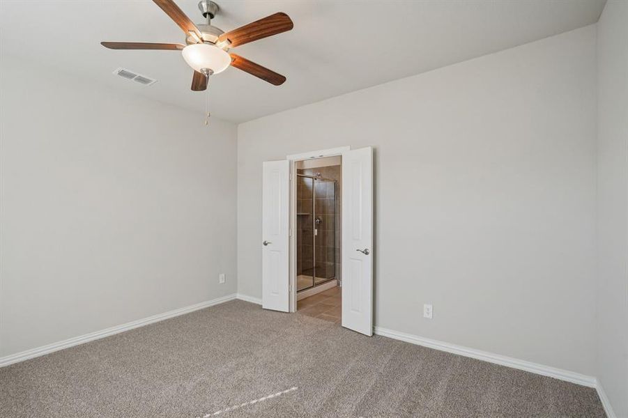 Carpeted empty room featuring ceiling fan and baseboards