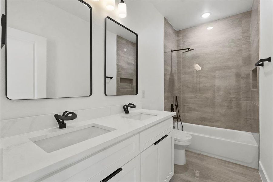 Bathroom featuring double vanity, shower / tub combination, light wood-type flooring, and recessed lighting