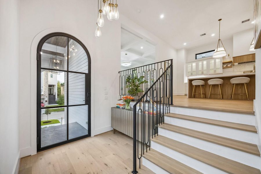 Another view of the formal entrance of the home.  The space is defined by soaring ceilings and an abundance of natural light streaming in through the large black-framed iron glass door with 6 divided lite windows, creating a bright and welcoming atmosphere.