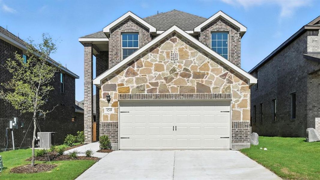View of front of house with driveway, stone siding, brick siding, and a front lawn