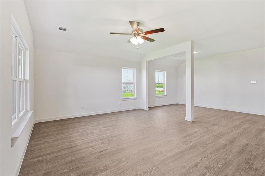 Empty room featuring light hardwood / wood-style floors, vaulted ceiling, ceiling fan, and ornate columns