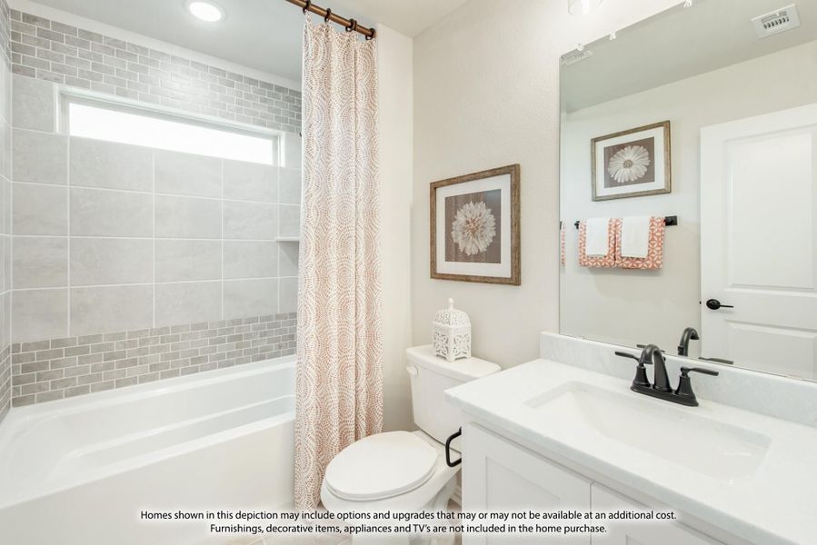 Bathroom with white vanity, soaking tub, gray tile surround, and patterned shower curtain Bathroom with white vanity, soaking tub, gray tile surround, and patterned shower curtain