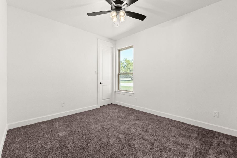 Spare room with dark carpet and a ceiling fan