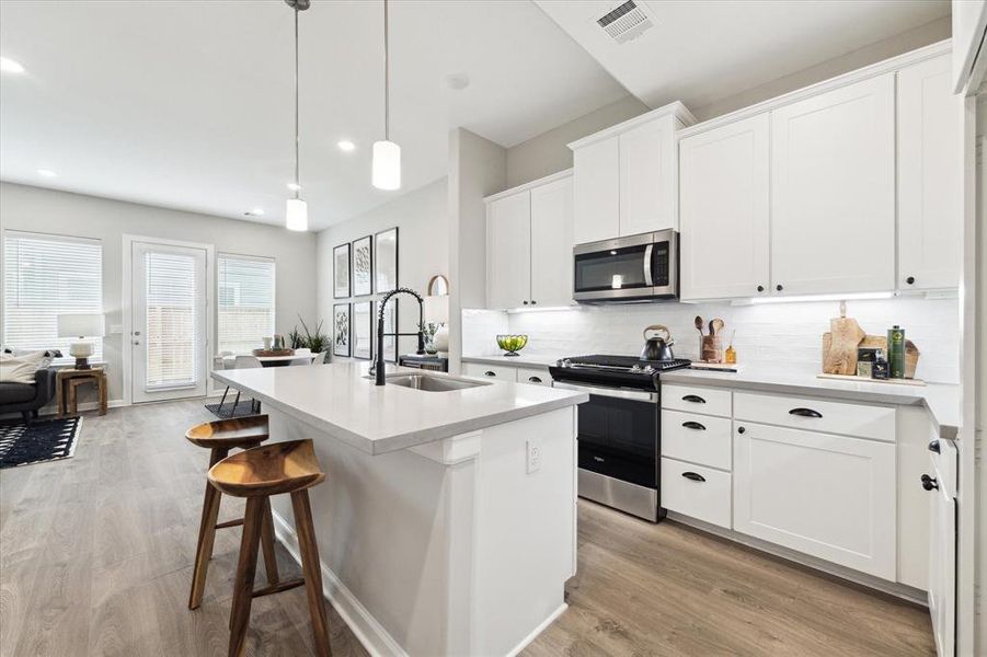 This beautifully designed kitchen is the heart of the home, featuring sleek quartz countertops and a striking designer backsplash that adds a touch of sophistication.