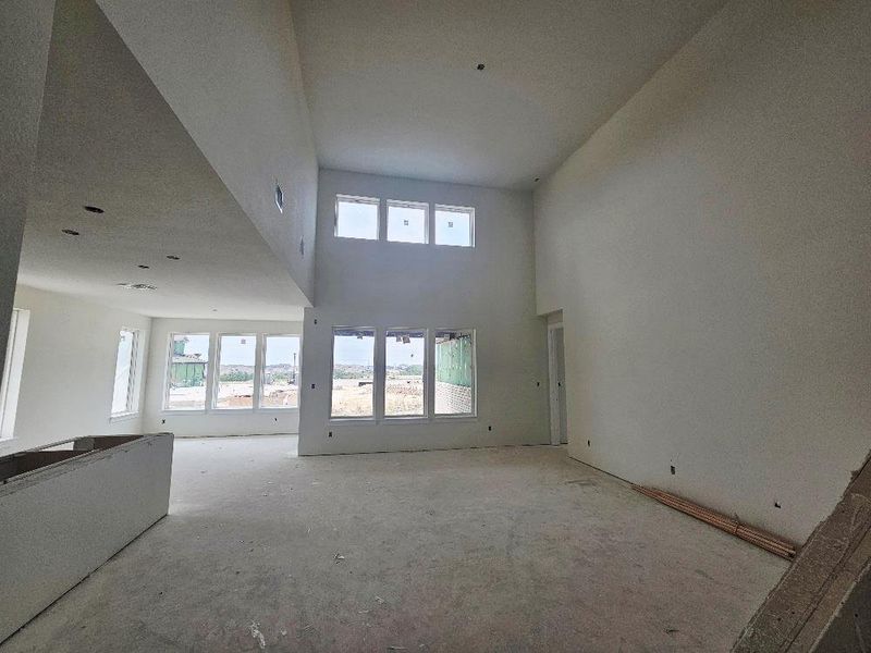 Unfurnished living room featuring plenty of natural light and a high ceiling Unfurnished living room featuring plenty of natural light and a high ceiling