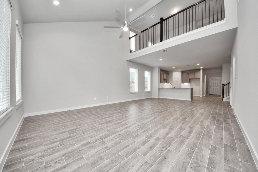 Bring your loved ones and guests together in the inviting living room! Boasting lofty high ceilings, recessed lighting, a stylish ceiling fan, custom paint, stunning flooring, and expansive windows that flood the space with ample natural light all day long. Sample photo of completed home with similar floor plan. Actual colors and selections may vary.