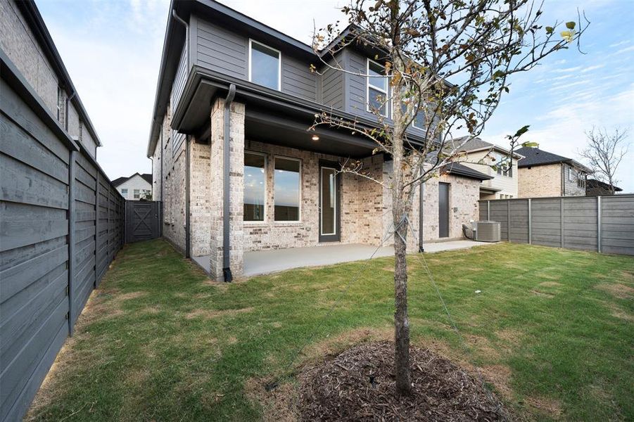 Rear view of property featuring a yard, cooling unit, and a patio