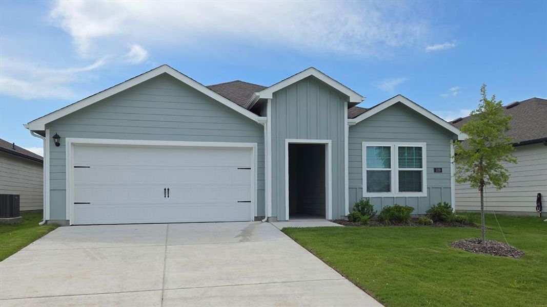 Exterior featuring light blue horizontal siding, vertical board and batten accents, a two-car garage with decorative hardware, a covered entry, and a manicured lawn with a young tree Exterior featuring light blue horizontal siding, vertical board and batten accents, a two-car garage with decorative hardware, a covered entry, and a manicured lawn with a young tree