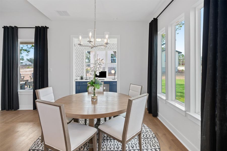 Dining space with light wood-style flooring, a chandelier, and plenty of natural light. The photos shown are of a completed home with the same floor plan and may not reflect the exact finishes, features, or layout of the home currently under construction.