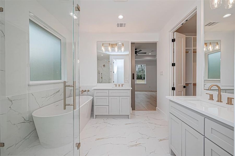 Primary bathroom features a modern design with a freestanding tub, glass-enclosed shower, and dual vanities.