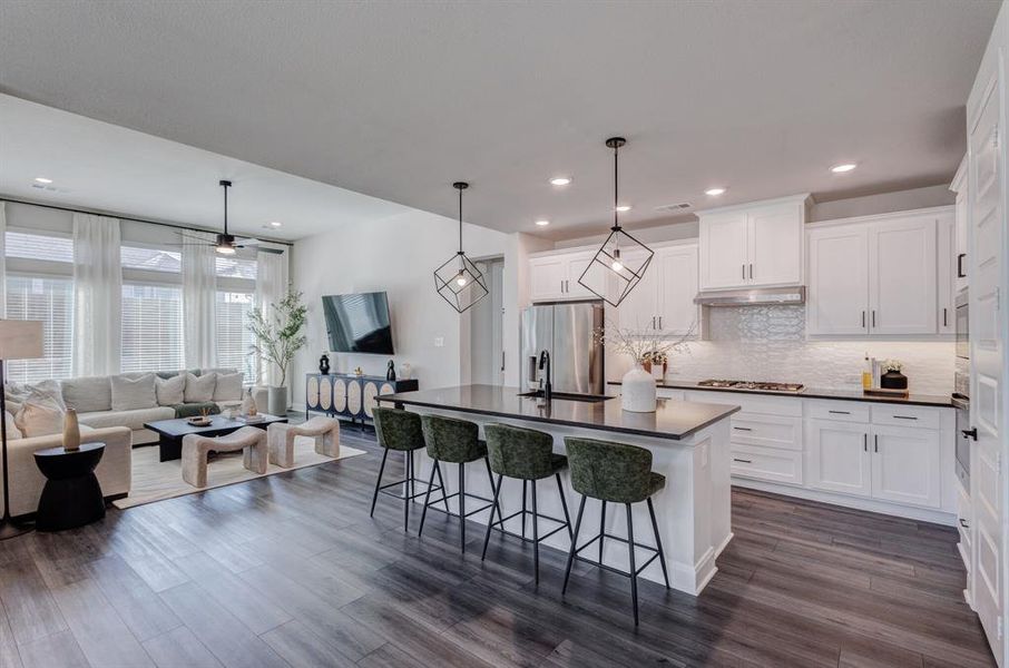 Kitchen with an island with sink, open floor plan, decorative light fixtures, a breakfast bar, and white cabinetry