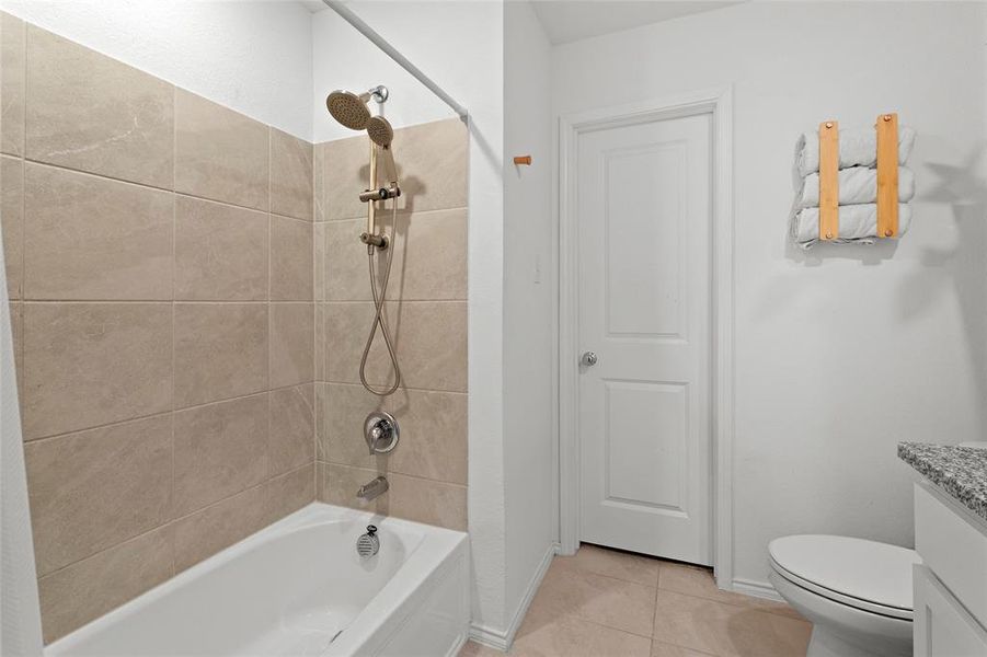Bathroom featuring vanity, shower / bathtub combination, and light tile patterned flooring