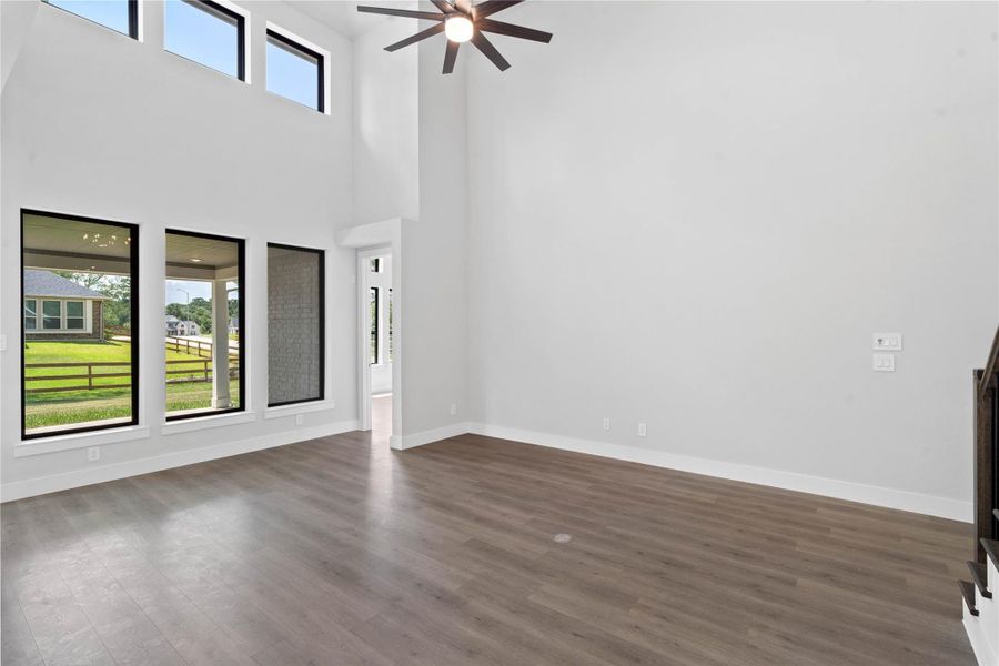 A grand great room with tall ceilings, ceiling fan, abundant natural light, and an open, inviting ambiance--perfect for gatherings, relaxation, and making memories.
