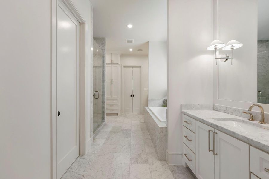 Spa-inspired primary bath featuring marble flooring, a glass walk-in shower, soaking tub, and elegant marble vanity with refined finishes throughout.