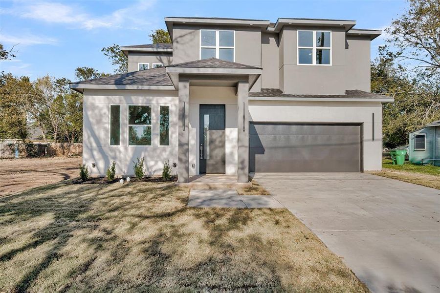 Prairie-style house featuring stucco siding, a garage, driveway, and roof with shingles