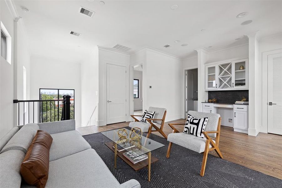 The large game room features a built in concession center with drawers and cabinets, bottle storage, glass-front display, and an optional upgrade to include a beverage refrigerator. Image of a previously completed home in the community.