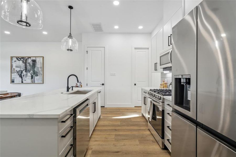 Elegant kitchen with an oversized farmhouse sink, modern pendant lighting, and energy-efficient stainless steel appliances.