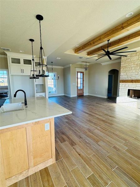 Kitchen featuring beam ceiling, hardwood / wood-style flooring, a kitchen island with sink, and sink