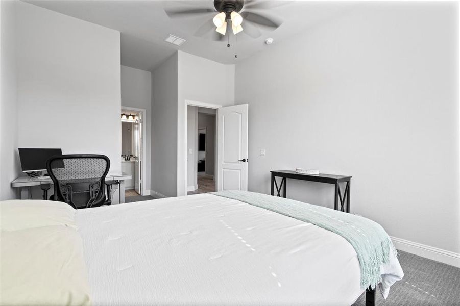 Carpeted bedroom with ceiling fan and a high ceiling