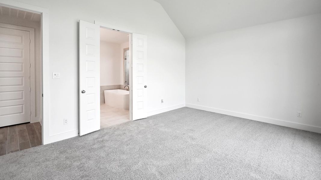 Unfurnished bedroom featuring carpet flooring, lofted ceiling, baseboards, and connected bathroom Unfurnished bedroom featuring carpet flooring, lofted ceiling, baseboards, and connected bathroom