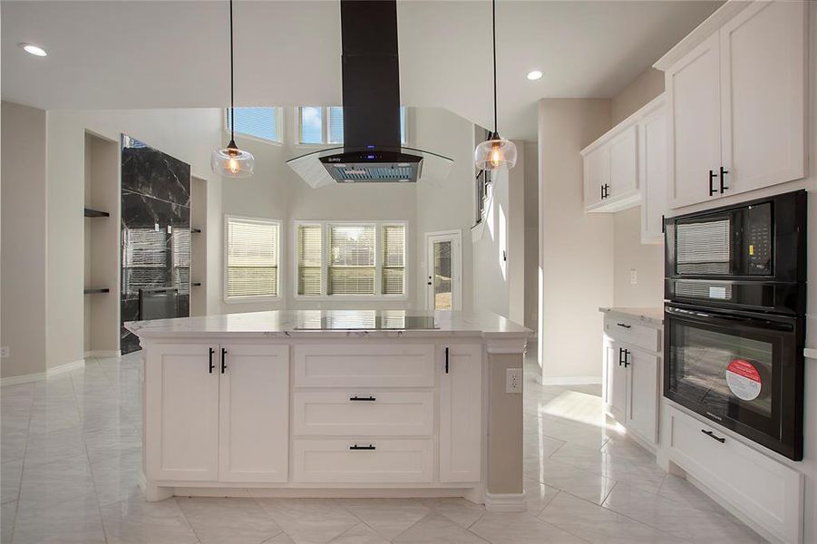 Kitchen featuring extractor fan, white cabinetry, hanging light fixtures, a center island, and black appliances