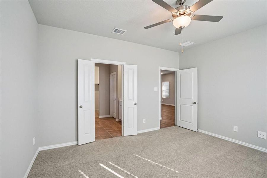 Unfurnished bedroom featuring light carpet, a ceiling fan, and connected bathroom