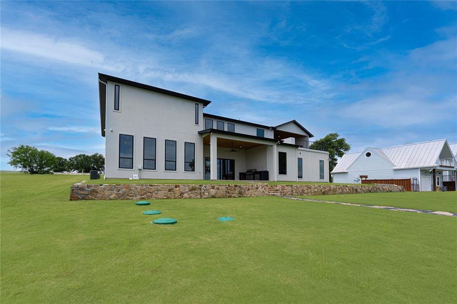 Back of property featuring a ceiling fan, a yard, and stucco siding Back of property featuring a ceiling fan, a yard, and stucco siding