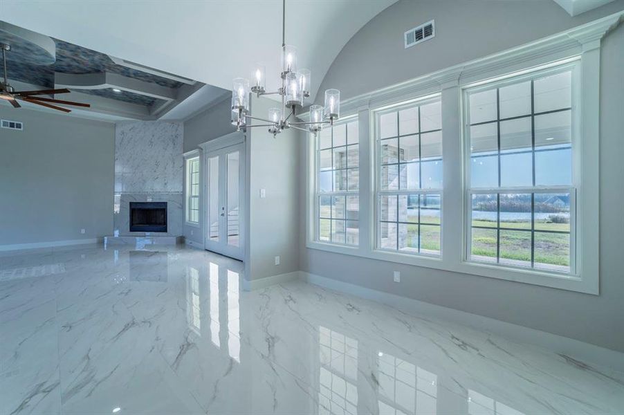 Unfurnished living room with a high end fireplace, marble tiled floors, a chandelier, a ceiling fan, and coffered ceiling