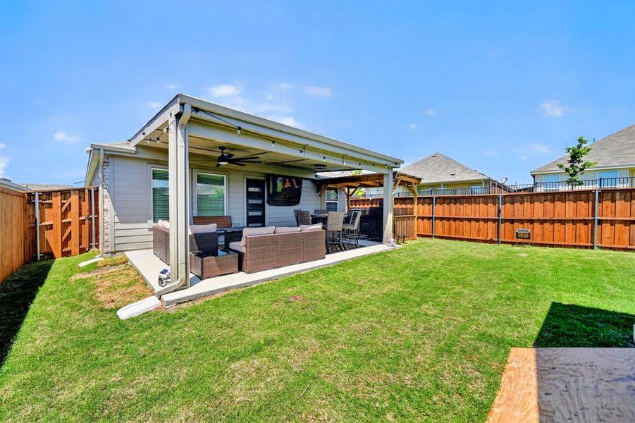 Rear patio featuring a covered outdoor living area with a ceiling fan and string lights