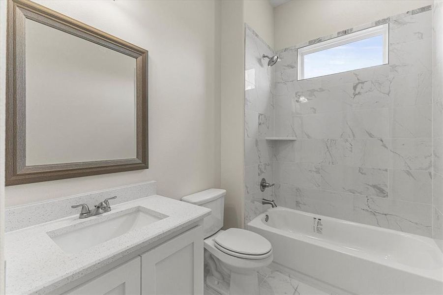 Full bathroom featuring marble finish floors, vanity, and washtub / shower combination