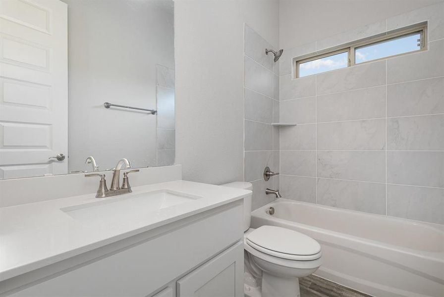 Full bathroom featuring vanity, hardwood / wood-style flooring, toilet, and tiled shower / bath